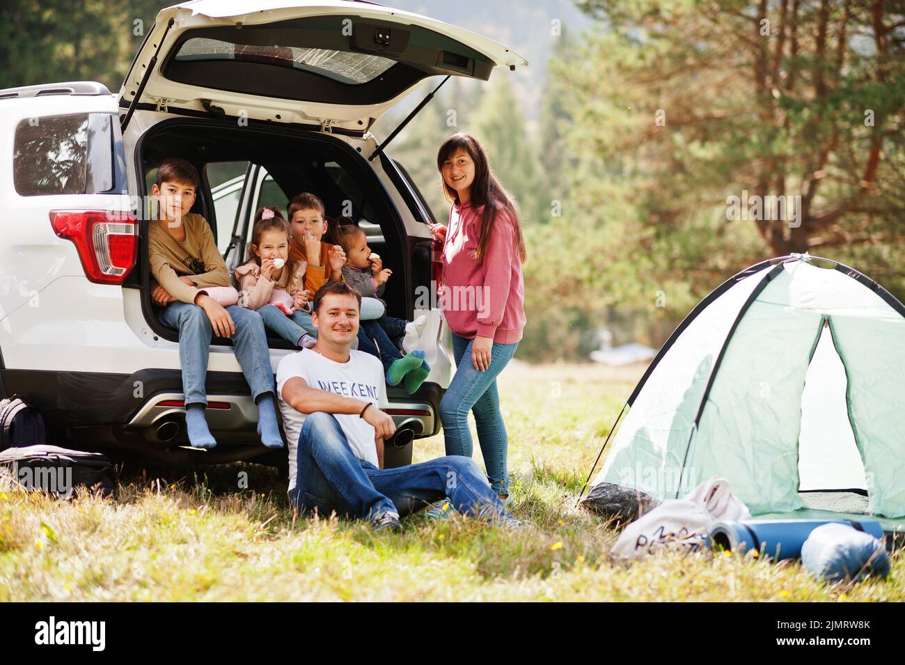 Large family of four kids. Children in trunk. Traveling by car in the mountains, atmosphere concept. American spirit. Stock Photo