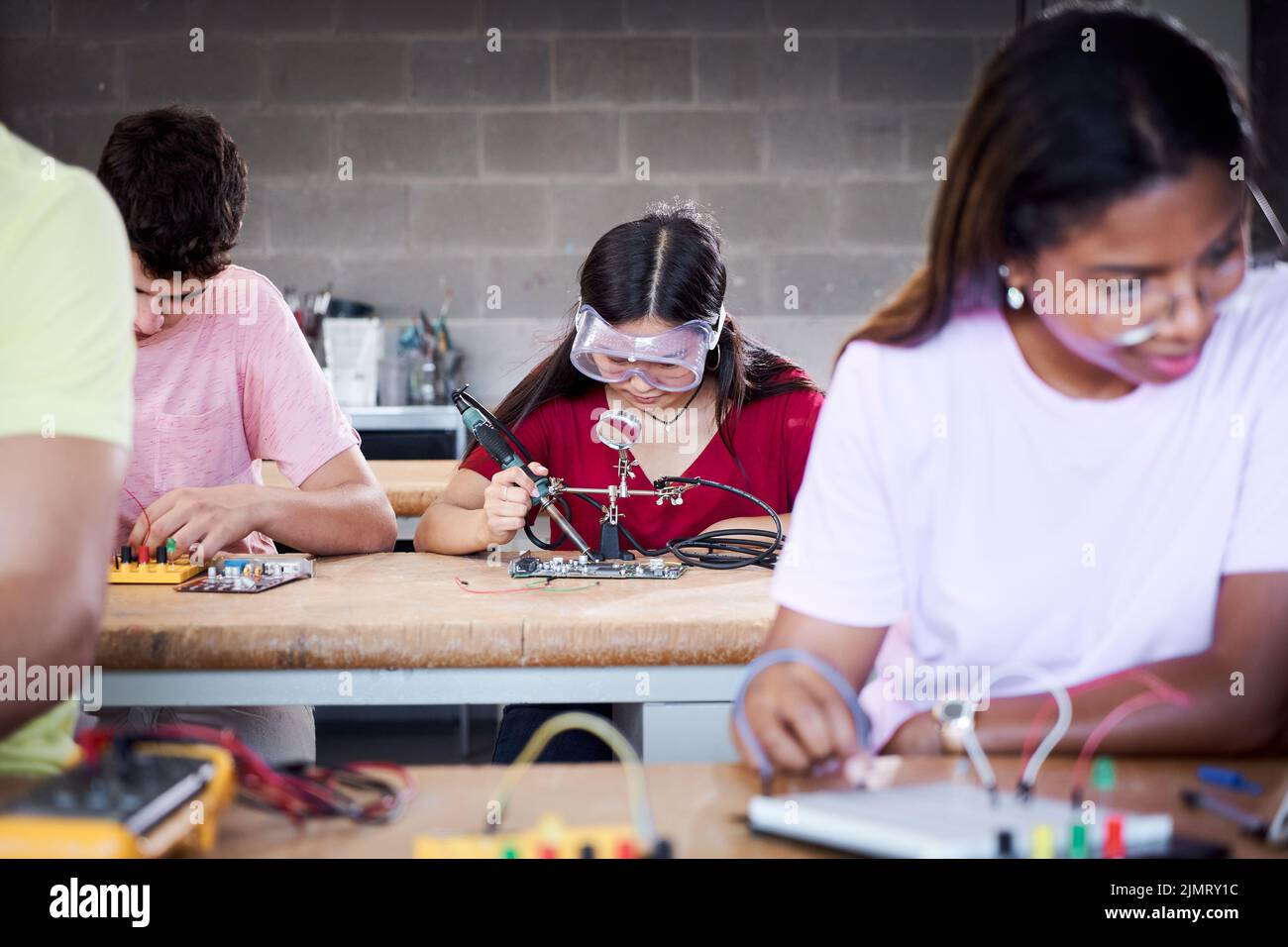 A group of technical college students are in the classroom studying, practicing soldering pieces of hardware on a circuit board. Concept of higher Stock Photo