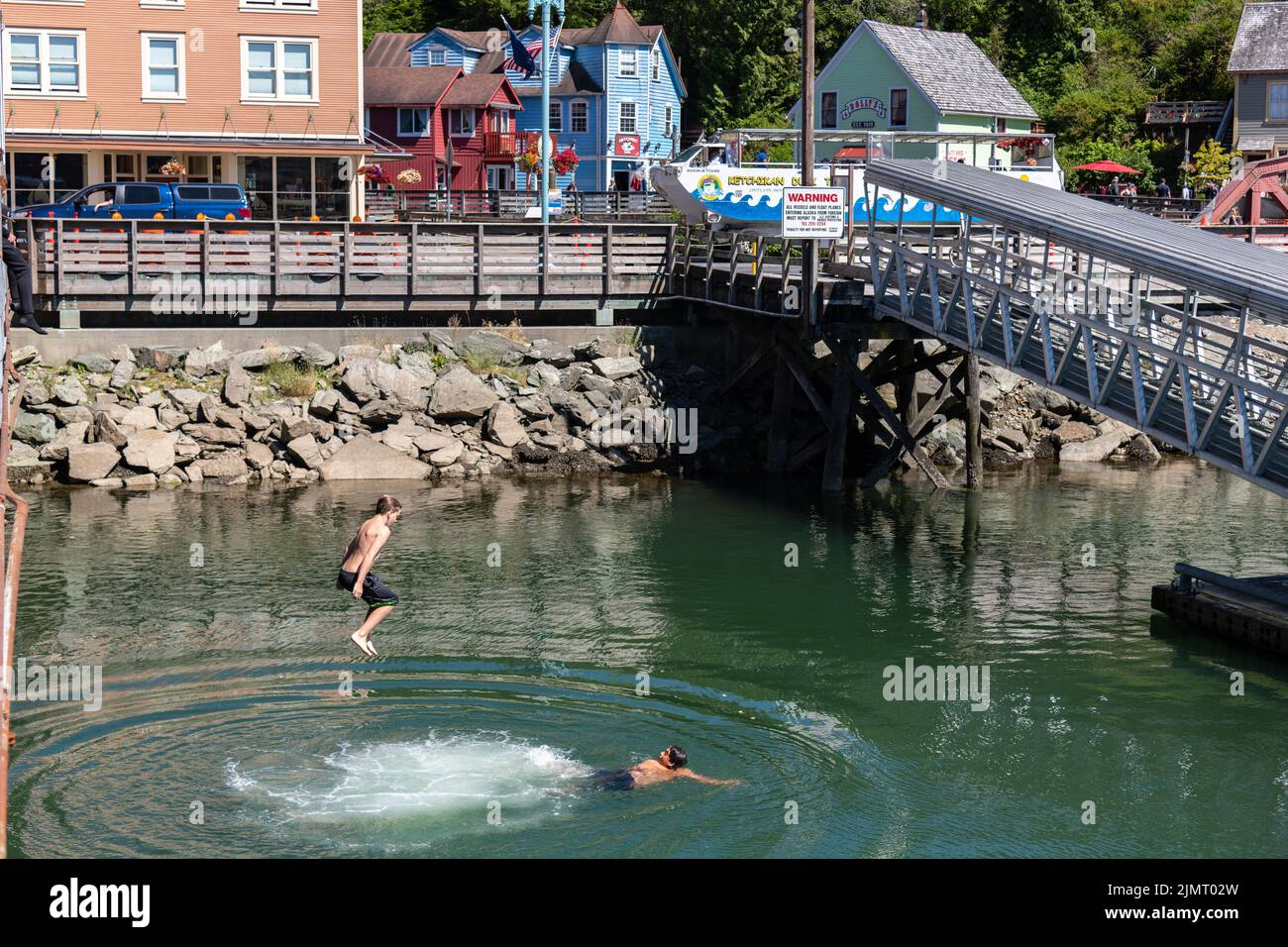 Young boys jump off the boardwalk into the water below at the historic Creek Street district built over Ketchikan Creek in Ketchikan, Alaska. Stock Photo