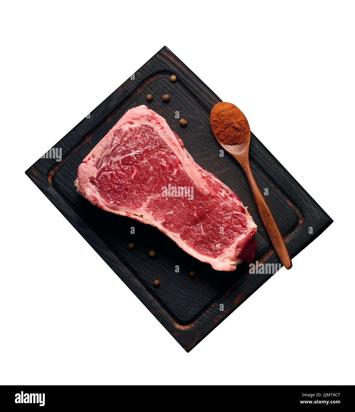 Raw juicy piece of beef meat on the bone lies on a wooden cutting board, spices for cooking on a black background. Meat tenderlo Stock Photo