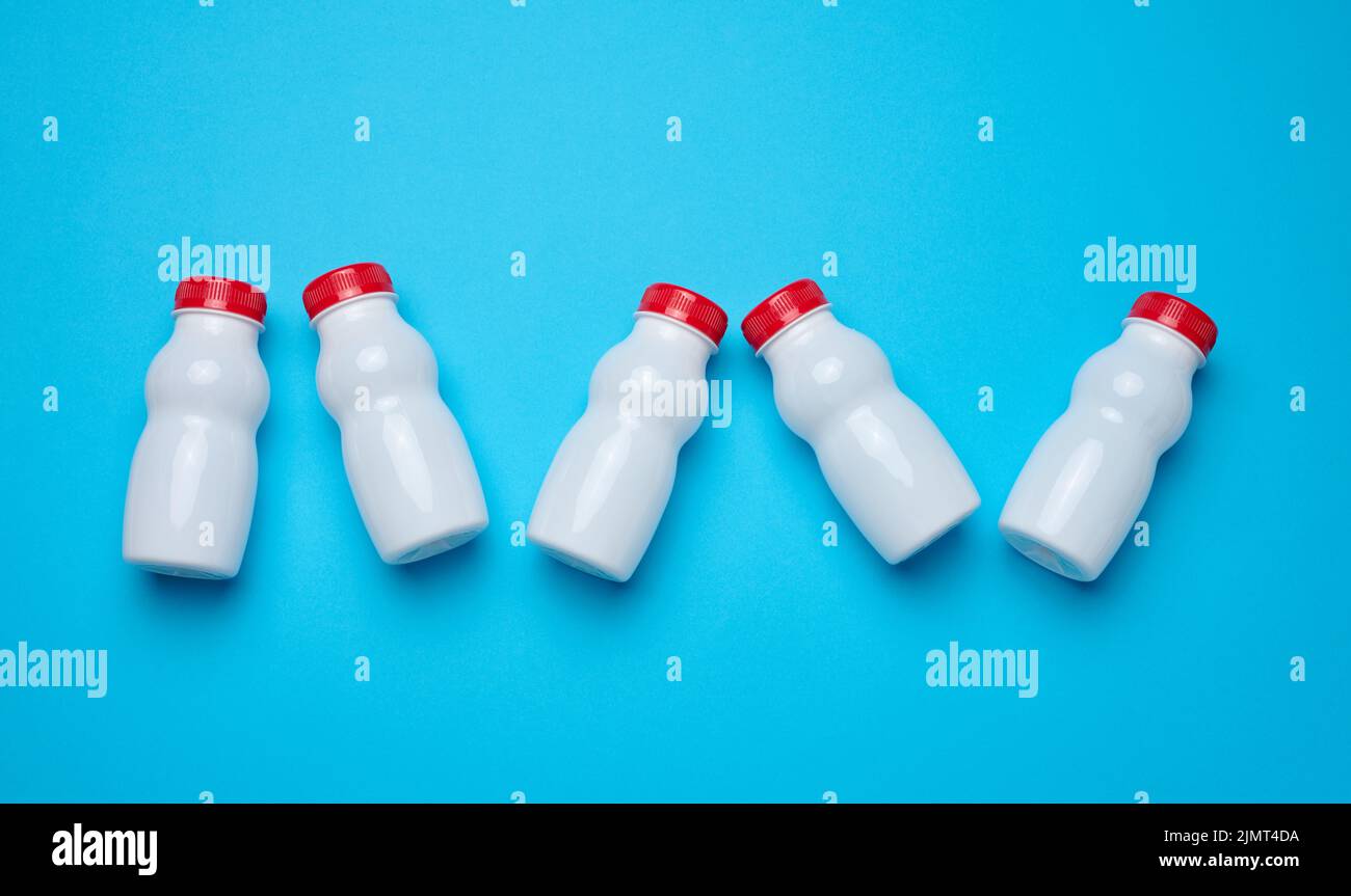 White plastic bottles with red caps for dairy products on a blue