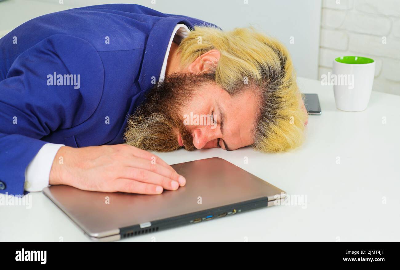 Tired businessman sleep on work desk. Office employee sleeping at workplace. Burnout and overwork. Stock Photo