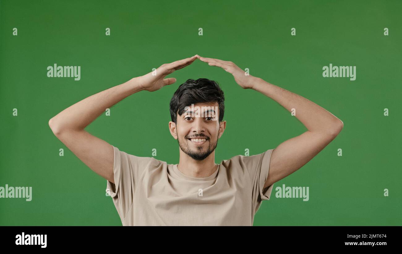 Hispanic young man arabian guy raise hands over head make house roof frame gesture with arms feel safe protection inside dream of home relocation Stock Photo