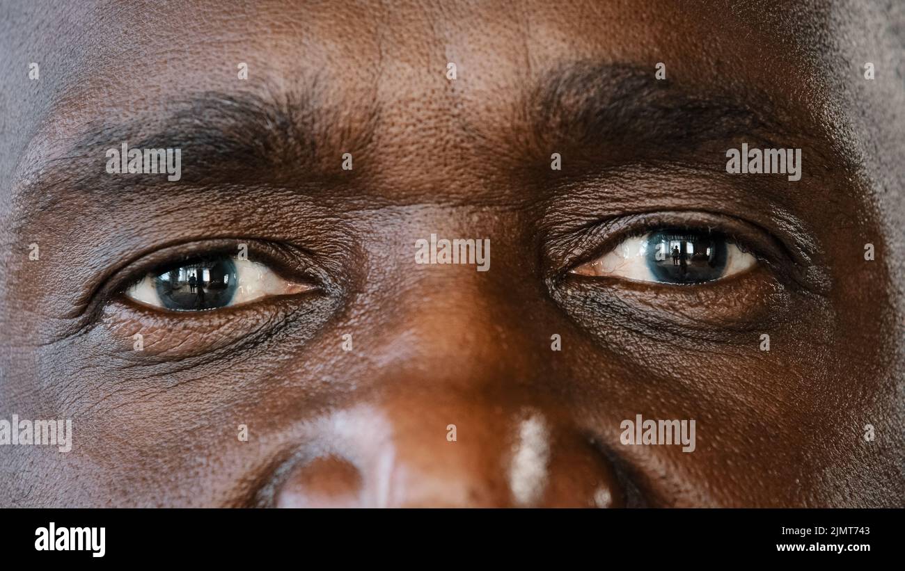 Extreme close up body part human male wrinkled face african american senior elderly adult man with dark iris eyesight masculine person looking at Stock Photo