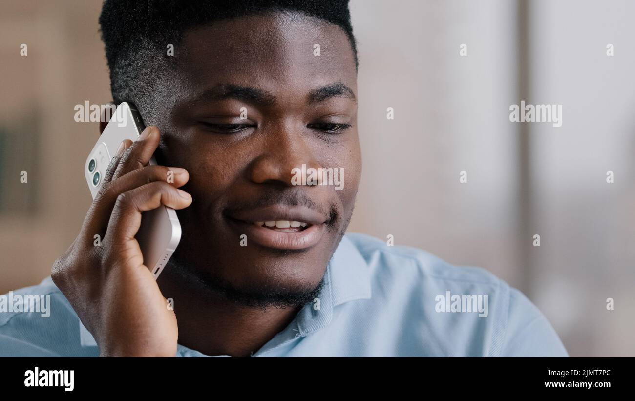 African american happy businessman guy talk on cellphone gadget communicate friendly with partner professional young male investor hold modern device Stock Photo