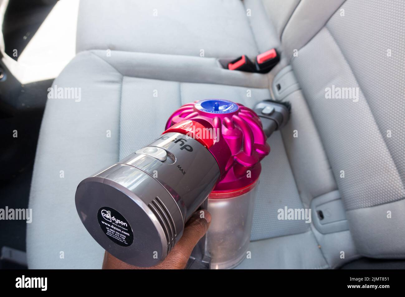 Adult male hands using a wireless vacuum cleaner on Car seat Stock Photo