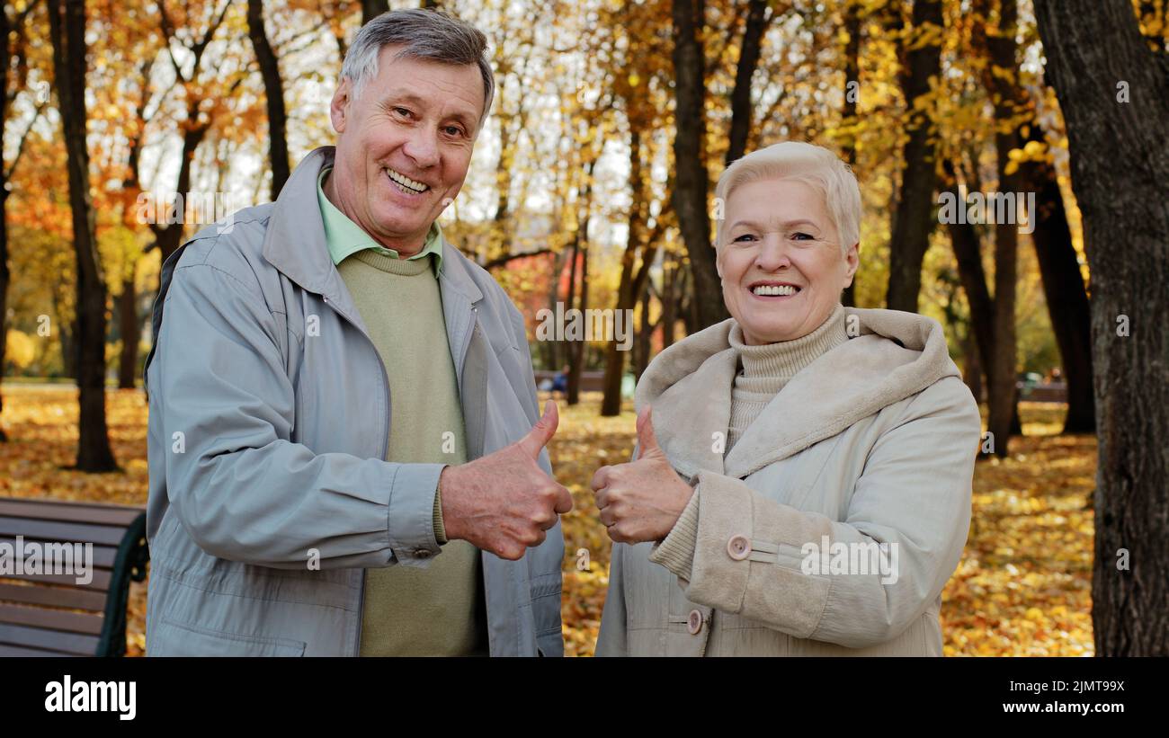 Portrait of happy elderly caucasian family wife husband senior grandparents stand outdoor in autumn park smiling old mature couple senior man woman sh Stock Photo