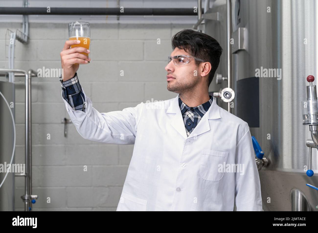 Brewer wearing white coat controlling process of beer fermentation