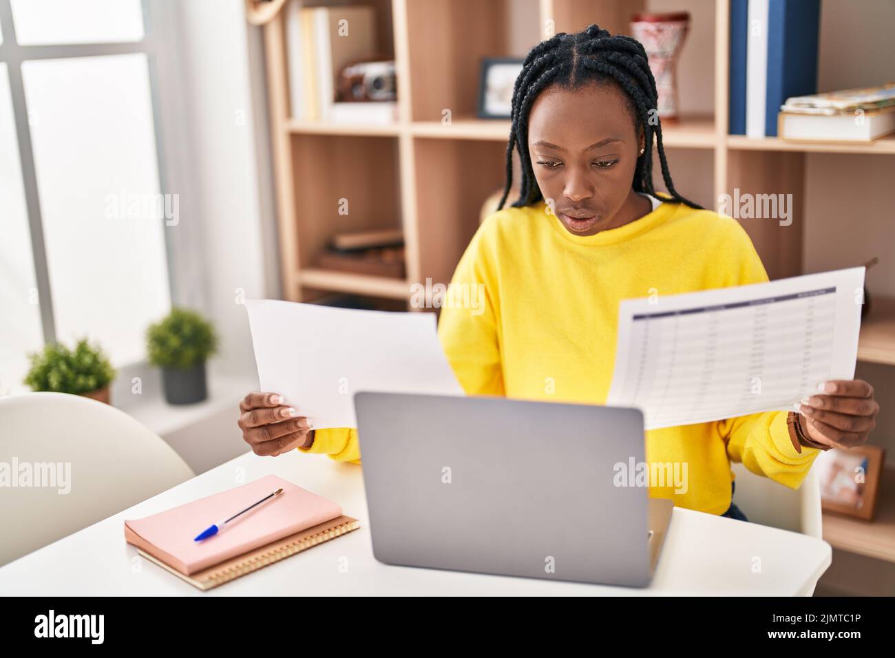 African american woman using laptop reading document at home Stock ...