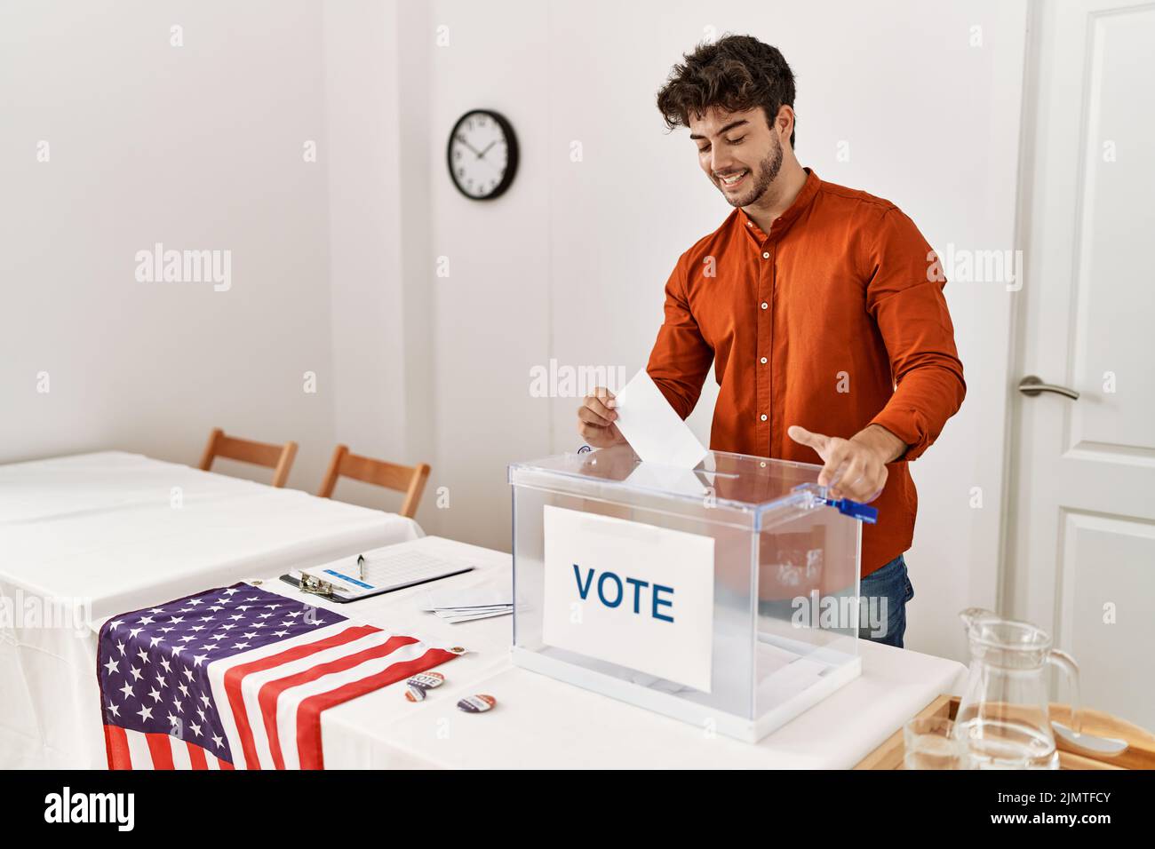 Young hispanic man smiling confident putting vote in box at electoral college Stock Photo