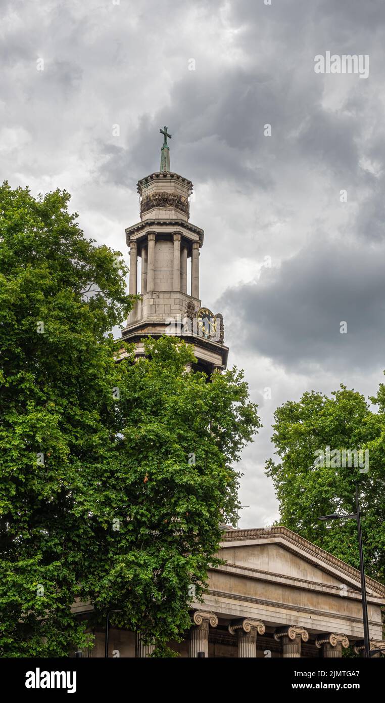 London, Great Britain - July 3, 2022: Beige stone tower and pediment above columns of St. Pancras New Church against heavy dark gray cloudscape and pa Stock Photo