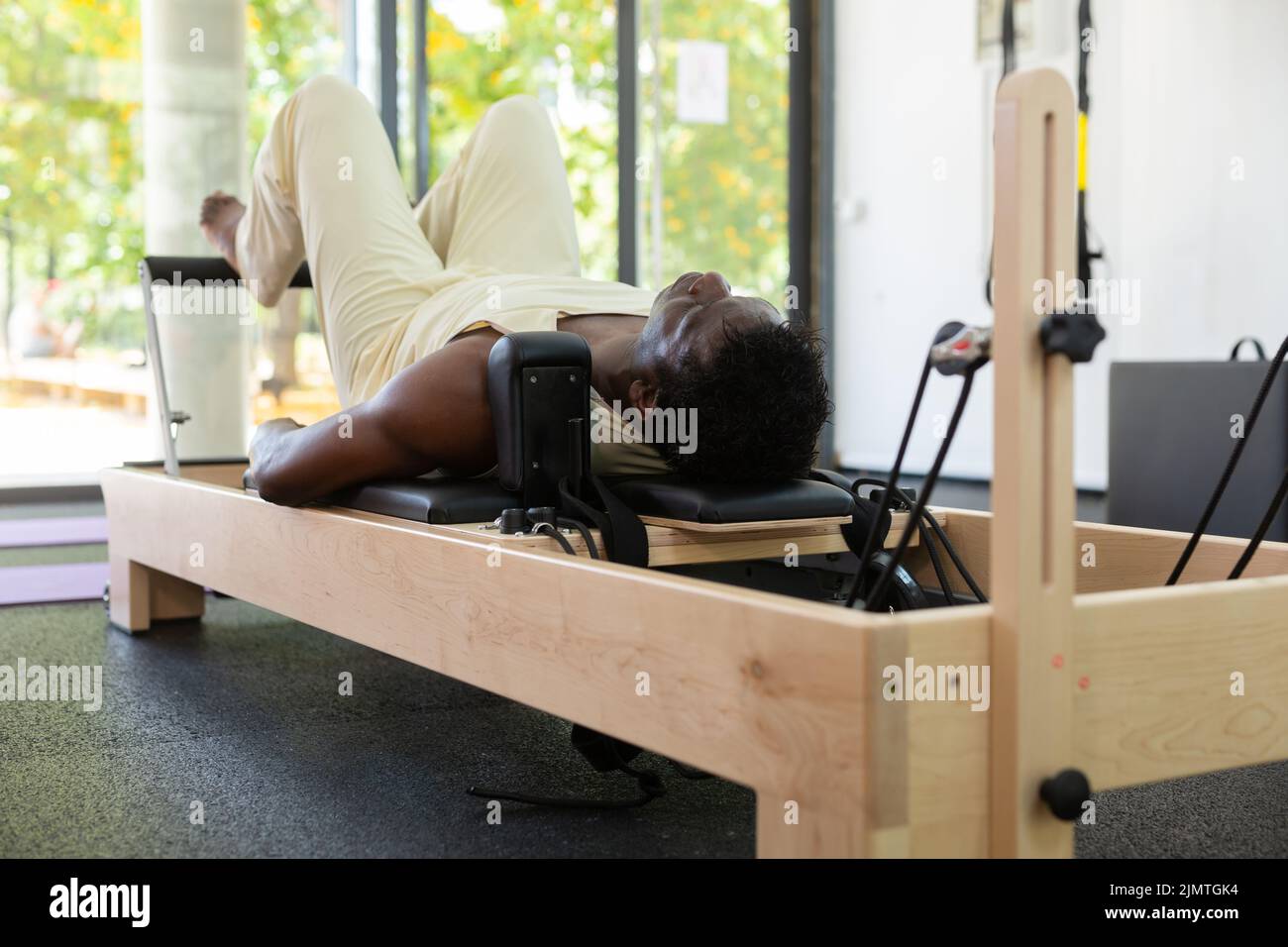 Man stretching body on pilates chair while doing forward bends during