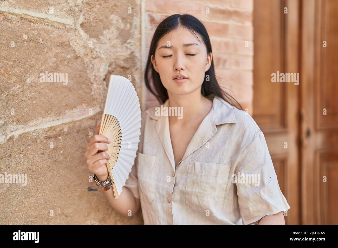 Chinese woman using handfan at street Stock Photo - Alamy