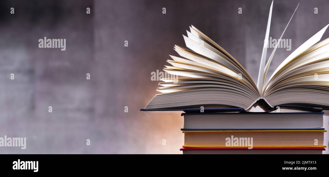 A composition with an open book lying on a stack of other books Stock Photo