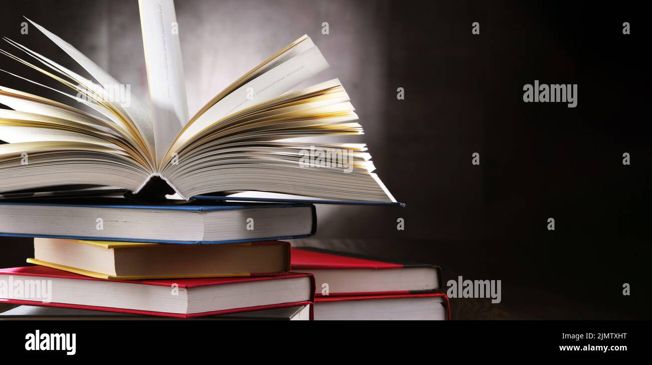A composition with an open book lying on a stack of other books Stock Photo