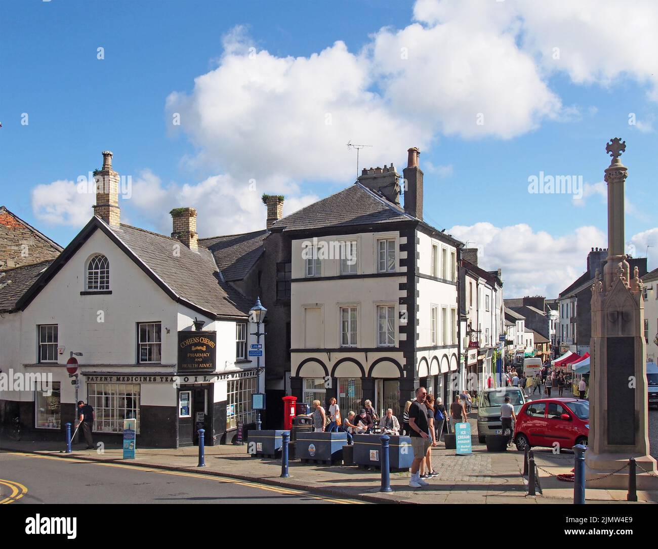 View of the town centre in ulverston cumbria with people walking past shops and the weekly market Stock Photo