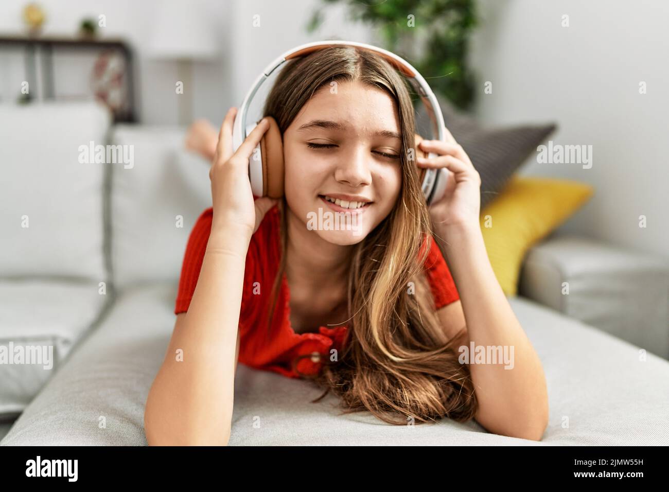 Adorable girl listening to music lying on sofa at home Stock Photo - Alamy