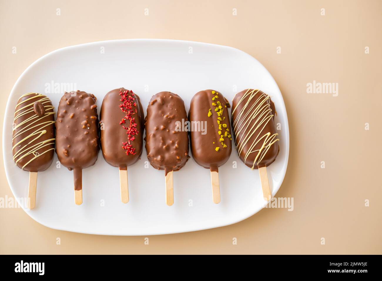 https://c8.alamy.com/comp/2JMW5JE/chocolate-cupcake-ice-creamchocolate-biscuits-on-a-stick-in-the-form-of-ice-cream-set-on-a-beige-background-2JMW5JE.jpg