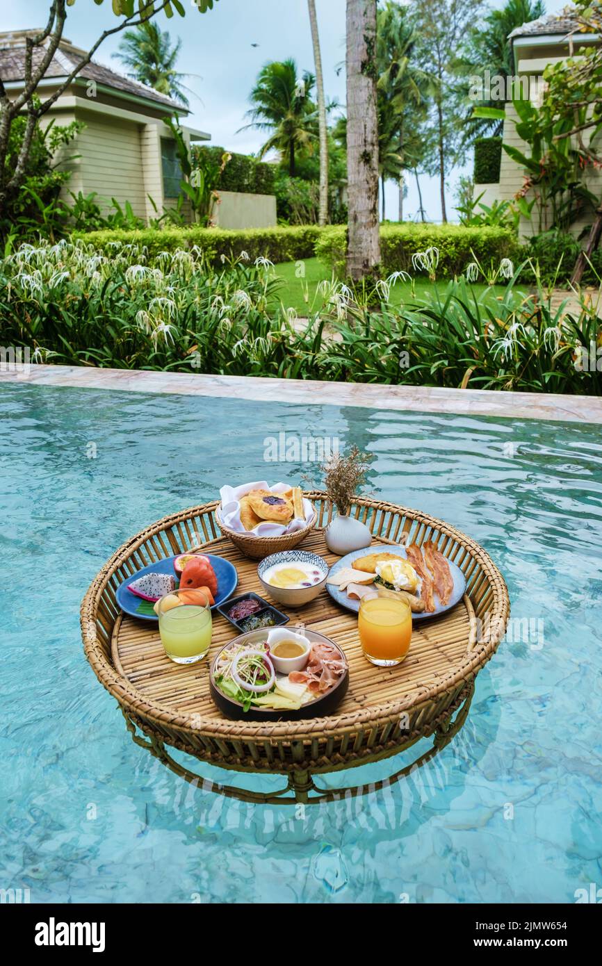 Couple men and woman on vacation in Thailand at an luxury pool villa having a floating breakfast Stock Photo