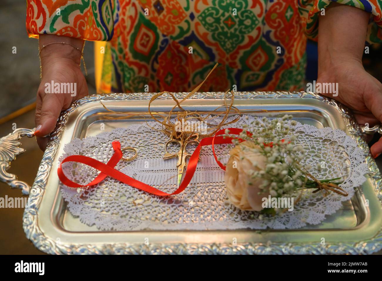 Engagement rings tied with red ribbon on a tray before wearing rings on