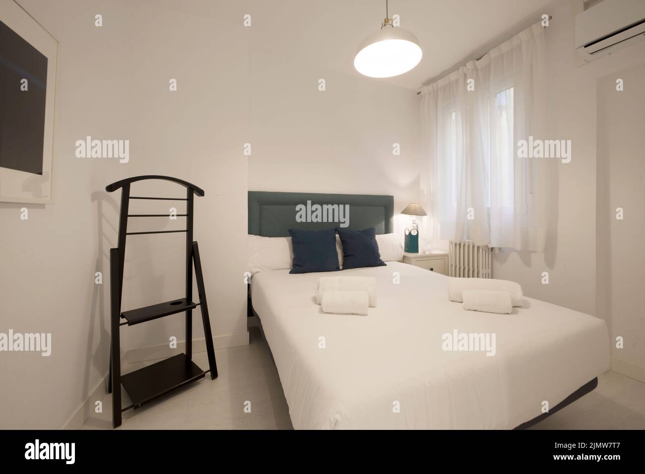 Bedroom with double bed with headboard upholstered in blue fabric with