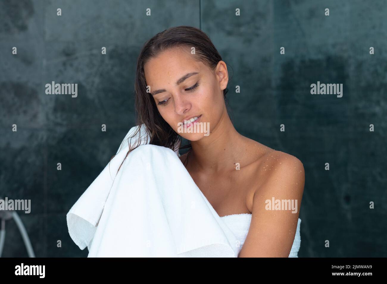 Close up of caucasian young woman drying her hair with a towel in the ...