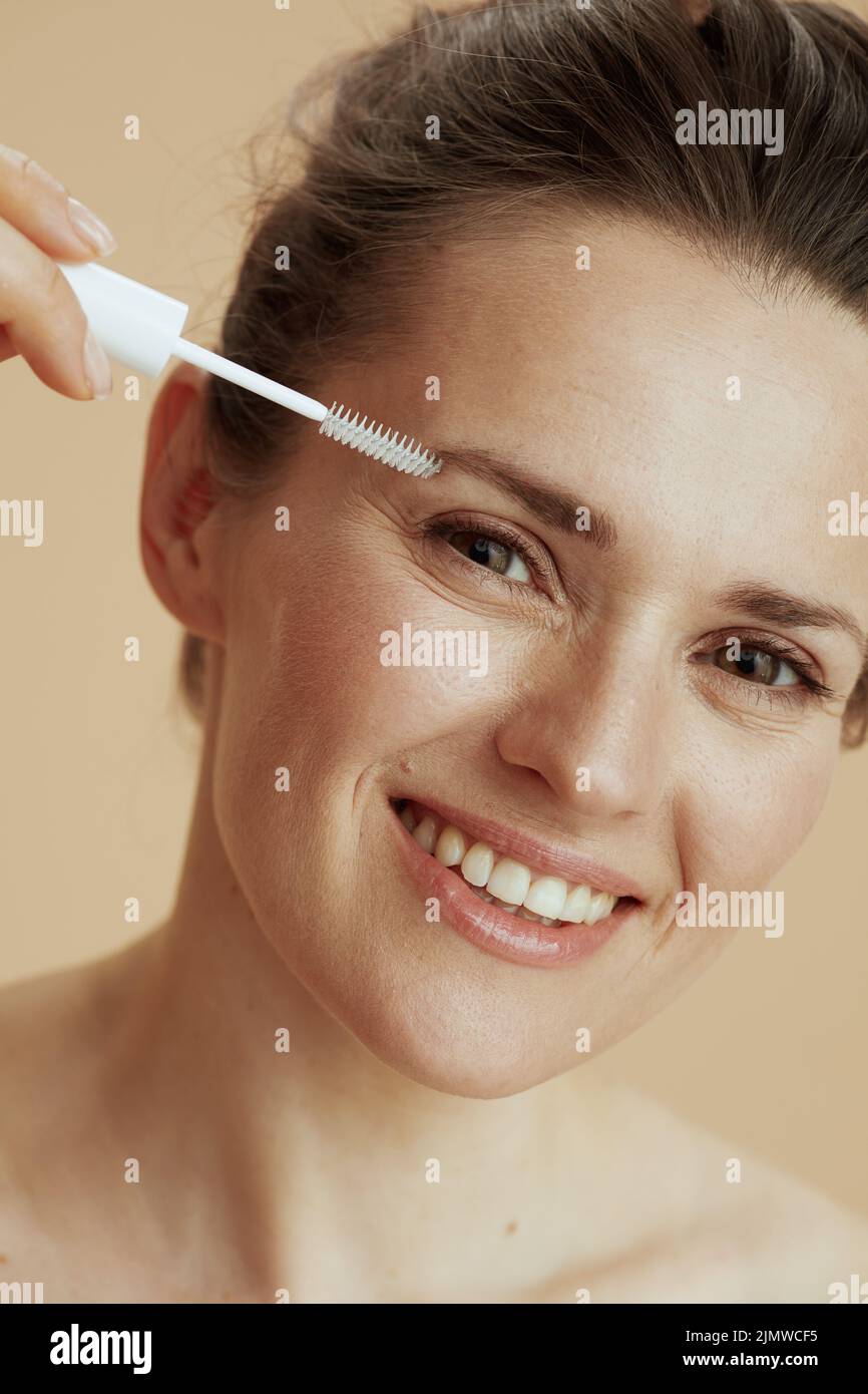 smiling modern woman with brow brush on beige background. Stock Photo