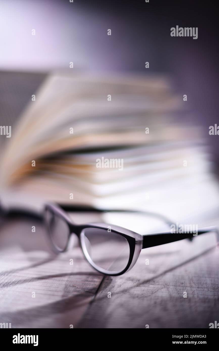 Composition with glasses and open book on the table. Stock Photo