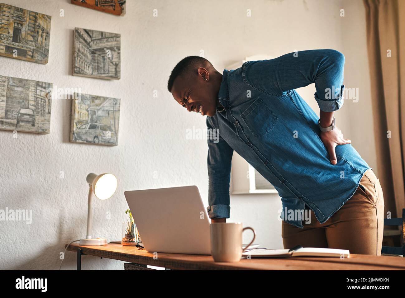 Back pain, ache and sore body with a business man suffering from bad posture. Feeling hurt with cramp or stiff spine from being overworked. Young male Stock Photo