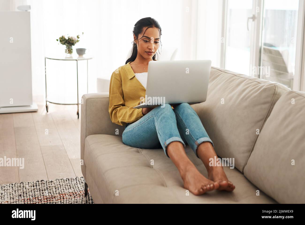 I love what I do. Full length shot of an attractive young businesswoman sitting on her couch and blogging from her laptop while at home. Stock Photo