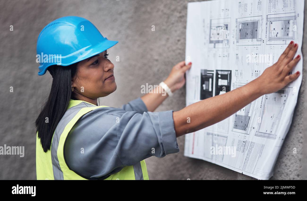 Shes got the plans laid out in front of her. an attractive young female construction worker