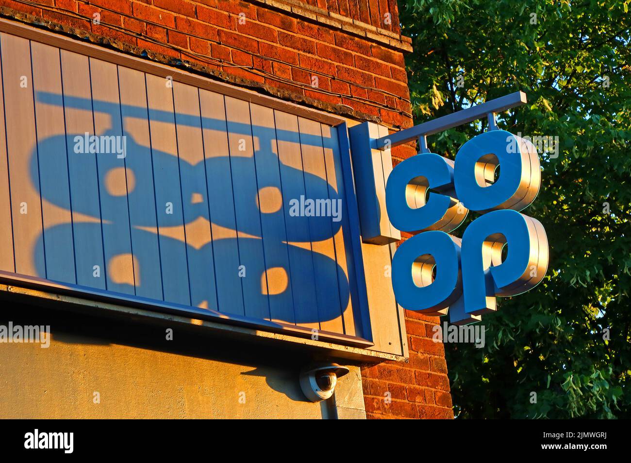 Sunset casting a shadow from CoOP sign, at 156 Knutsford Road, Grappenhall, Warrington, Cheshire, England, UK Stock Photo