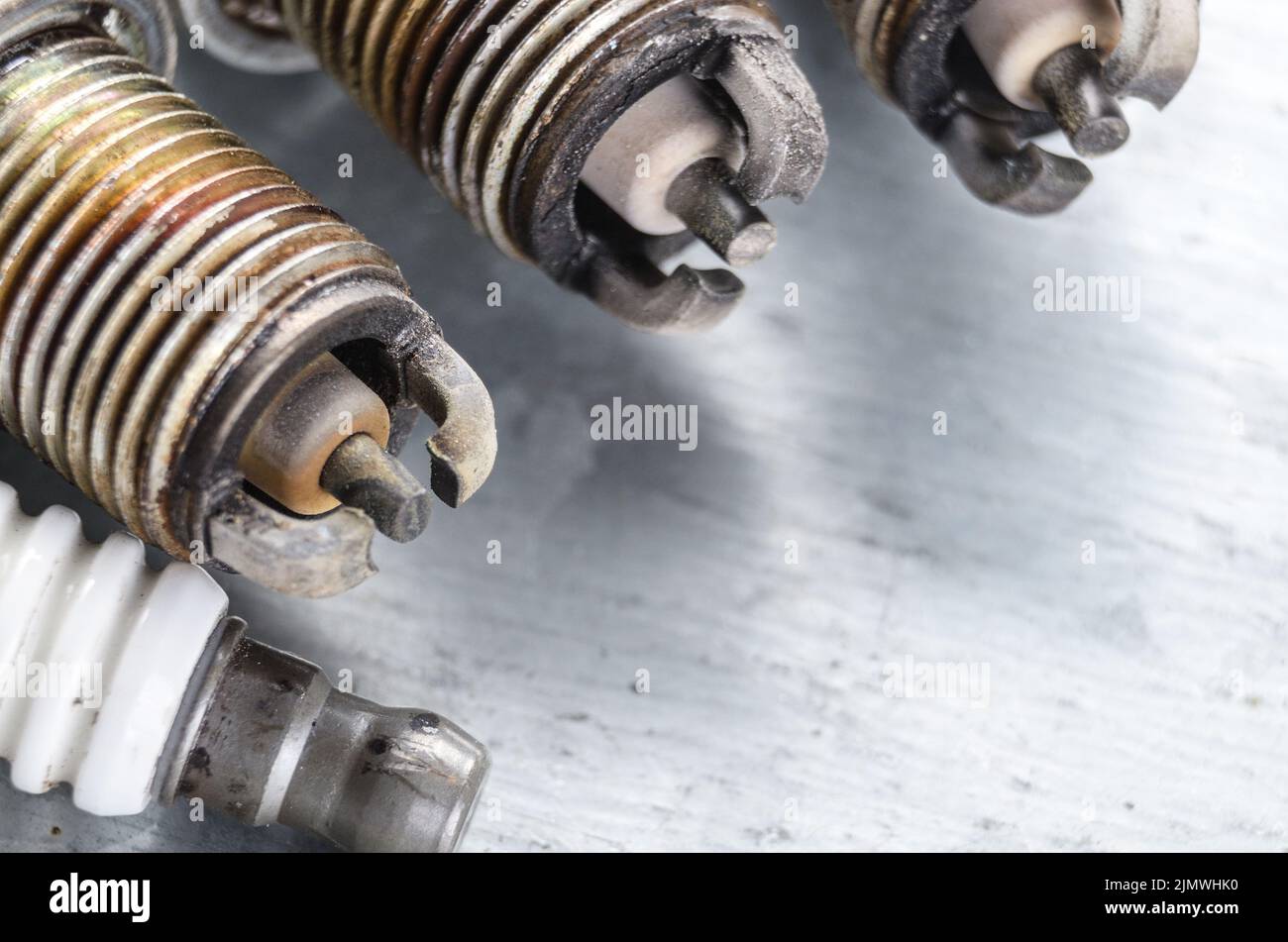 New and used spark plugs for internal combustion engine on metal background. Space for text Stock Photo