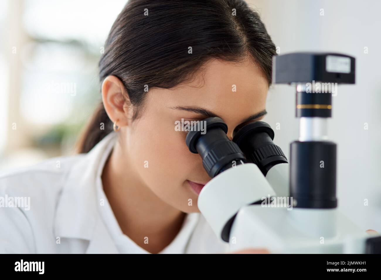 Things are a lot different under the lens. a young scientist using a microscope in a lab. Stock Photo