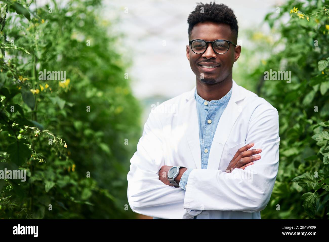 Who wouldnt love working in the fresh open air. Portrait of a handsome young botanist posing with his arms folded outdoors in nature. Stock Photo