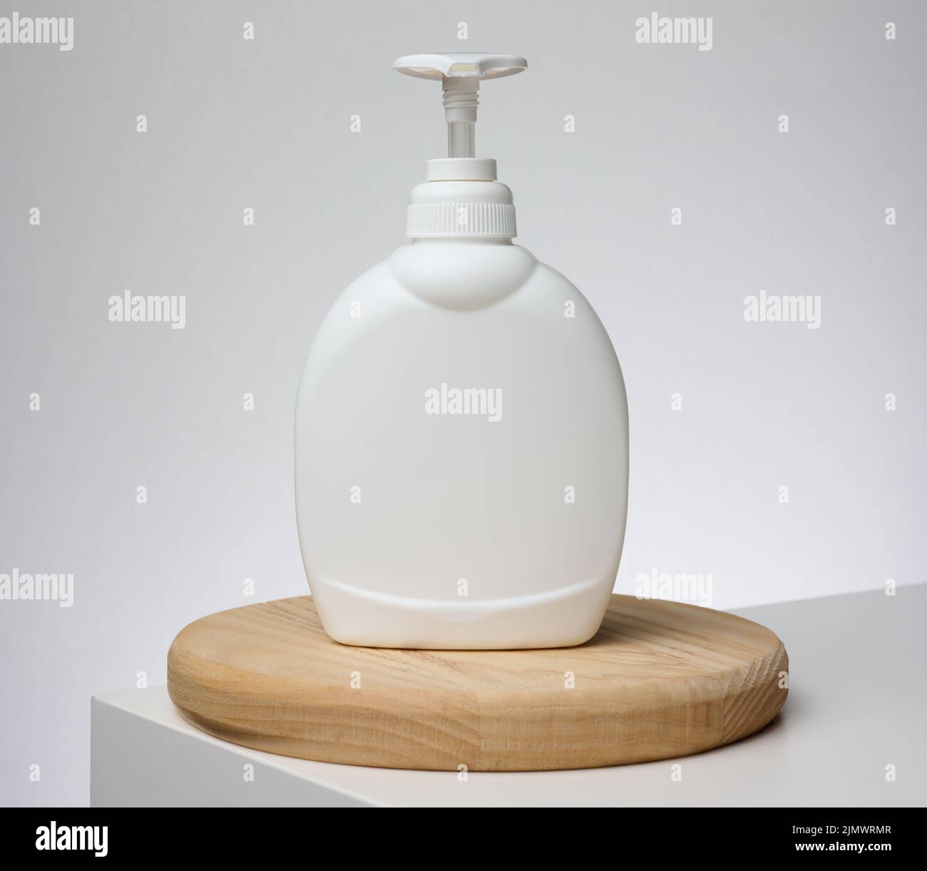 White plastic container with a pump for cosmetic liquid, liquid soap on the table Stock Photo