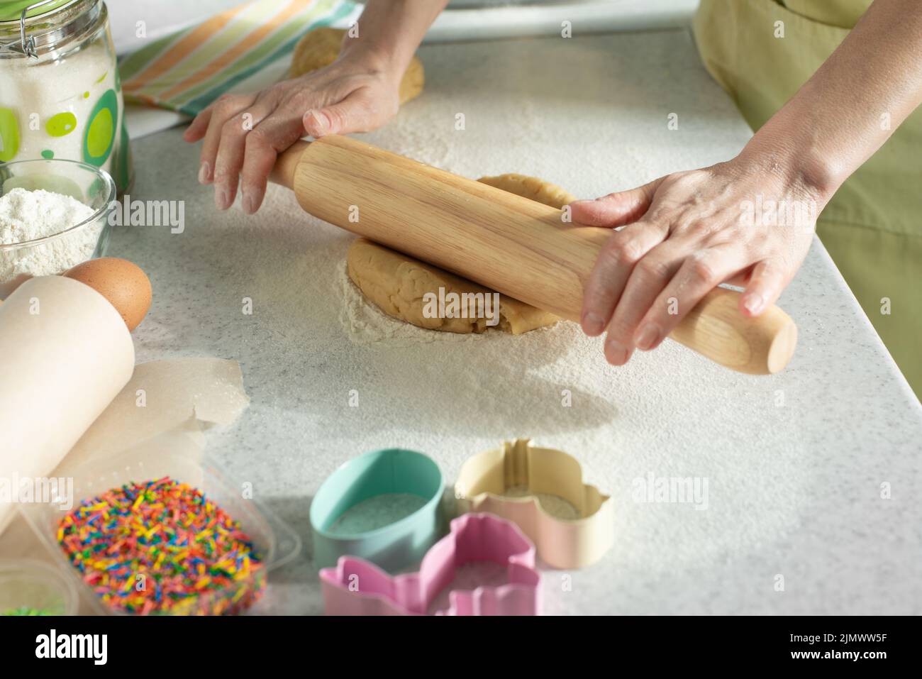 Female model rolls dough with rolling pin on kitchen table. Cookie