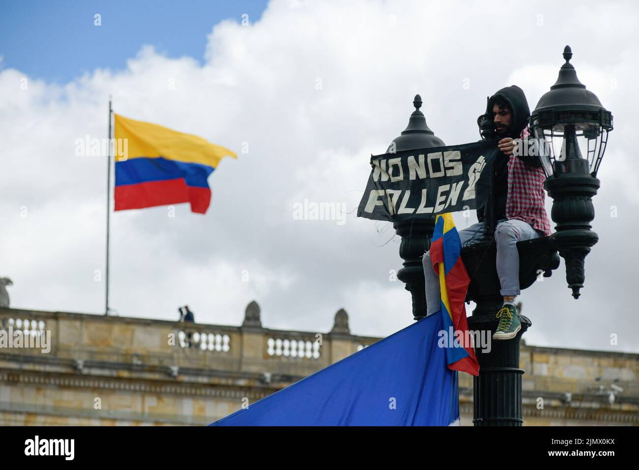 Bogota, Colombia. 07th Aug, 2022. A man on top of a lamp pole holds a