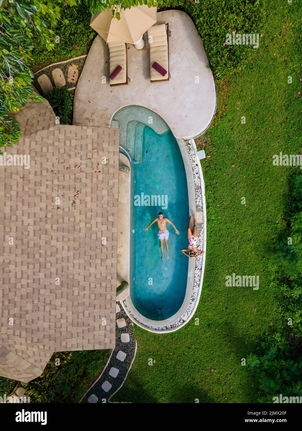 Couple European man and Asian woman in infinity pool in Thailand looking out over the ocean, luxury vacation in Thailand, privat Stock Photo