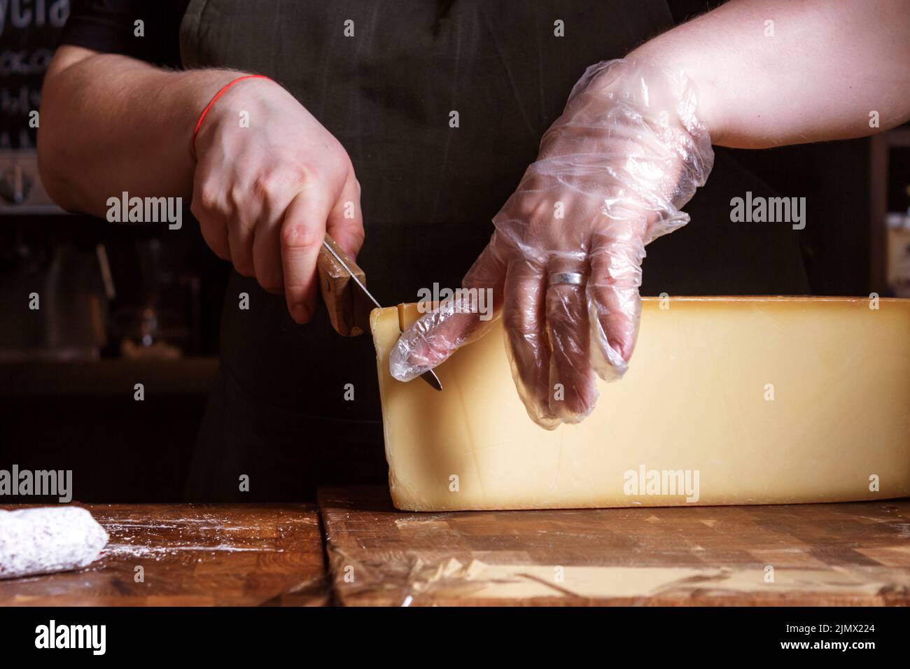 Saleswoman cutting cheese for sale. Cheese shop. Stock Photo