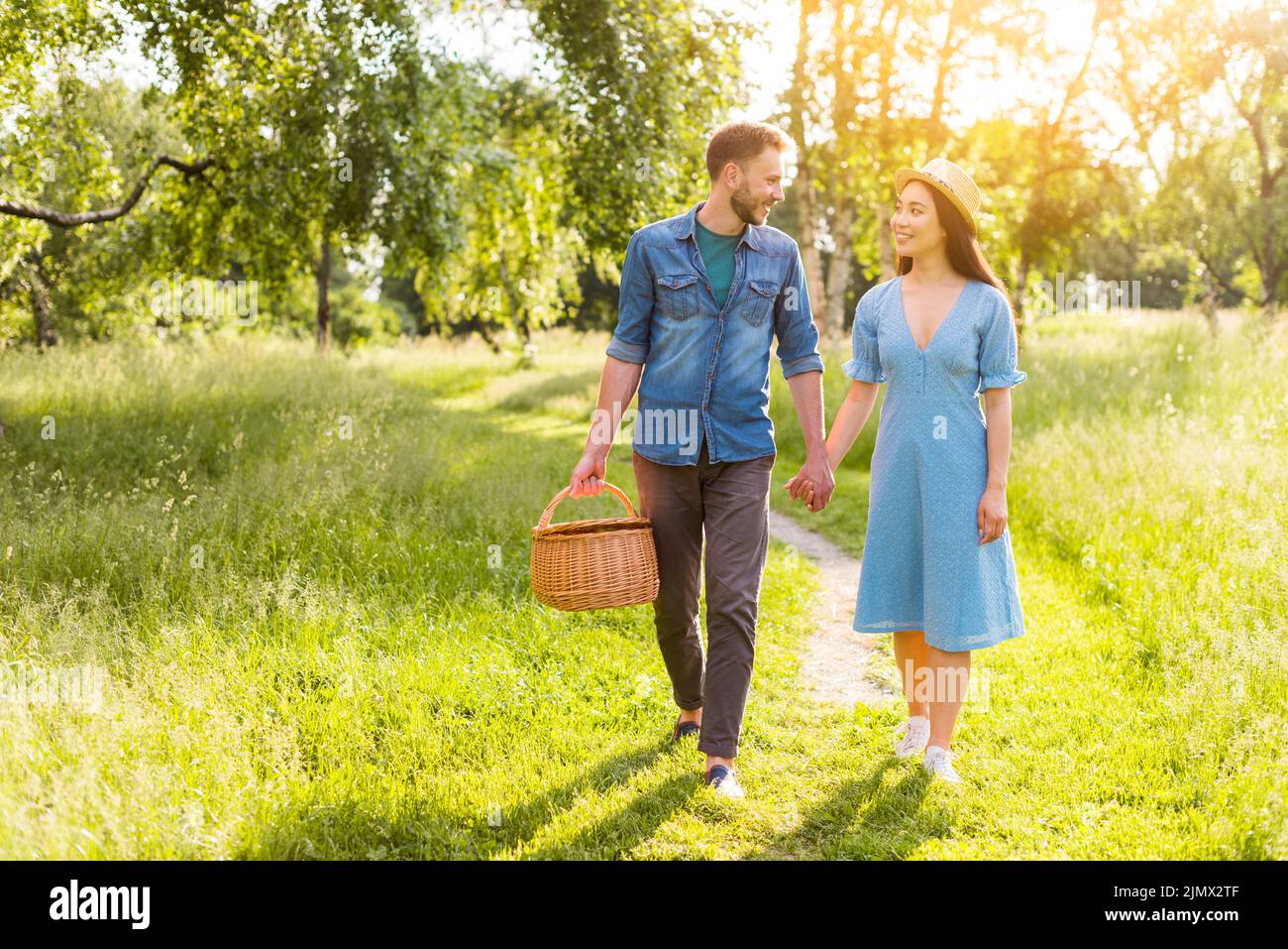 Young multiracial enamored couple walking park holding hands Stock Photo