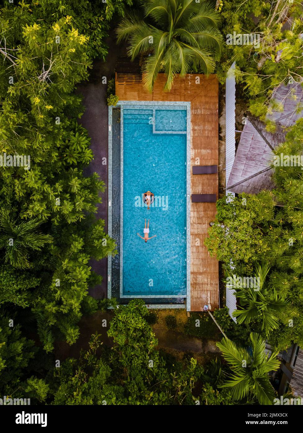 Couple men and woman in swimming pool in the jungle of Krabi Thailand, aerial view with drone above swimming pool in jungle of T Stock Photo