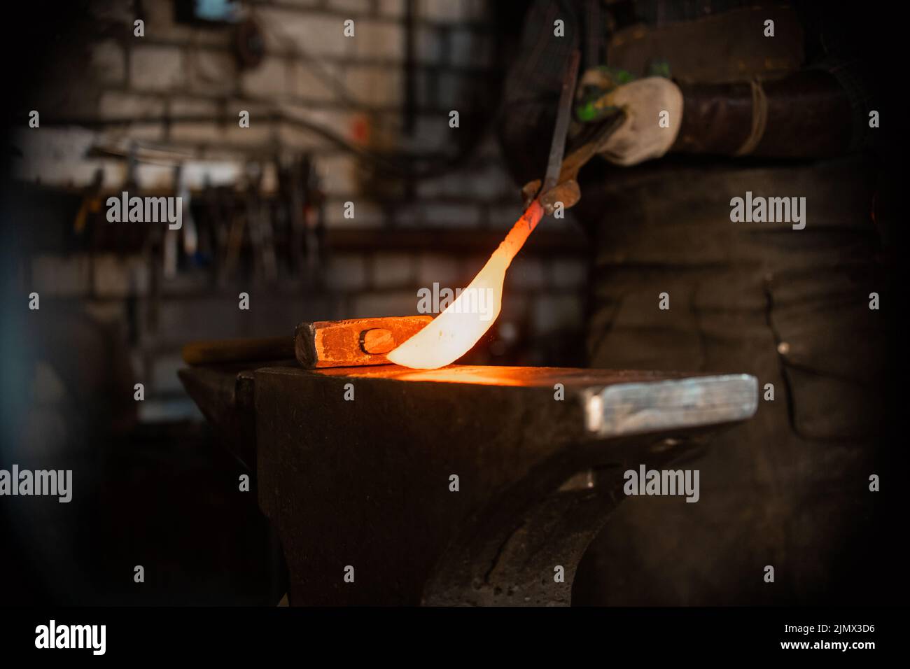 Forging a knife out of the hot metal - holding the knife between the forceps Stock Photo