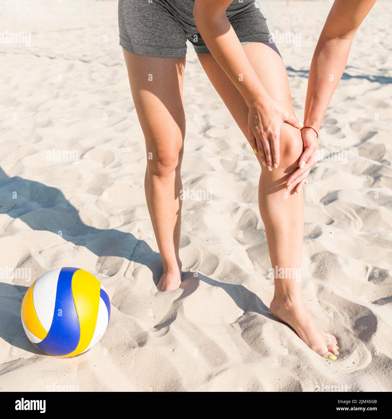 Female volleyball player hurting her knee while playing Stock Photo
