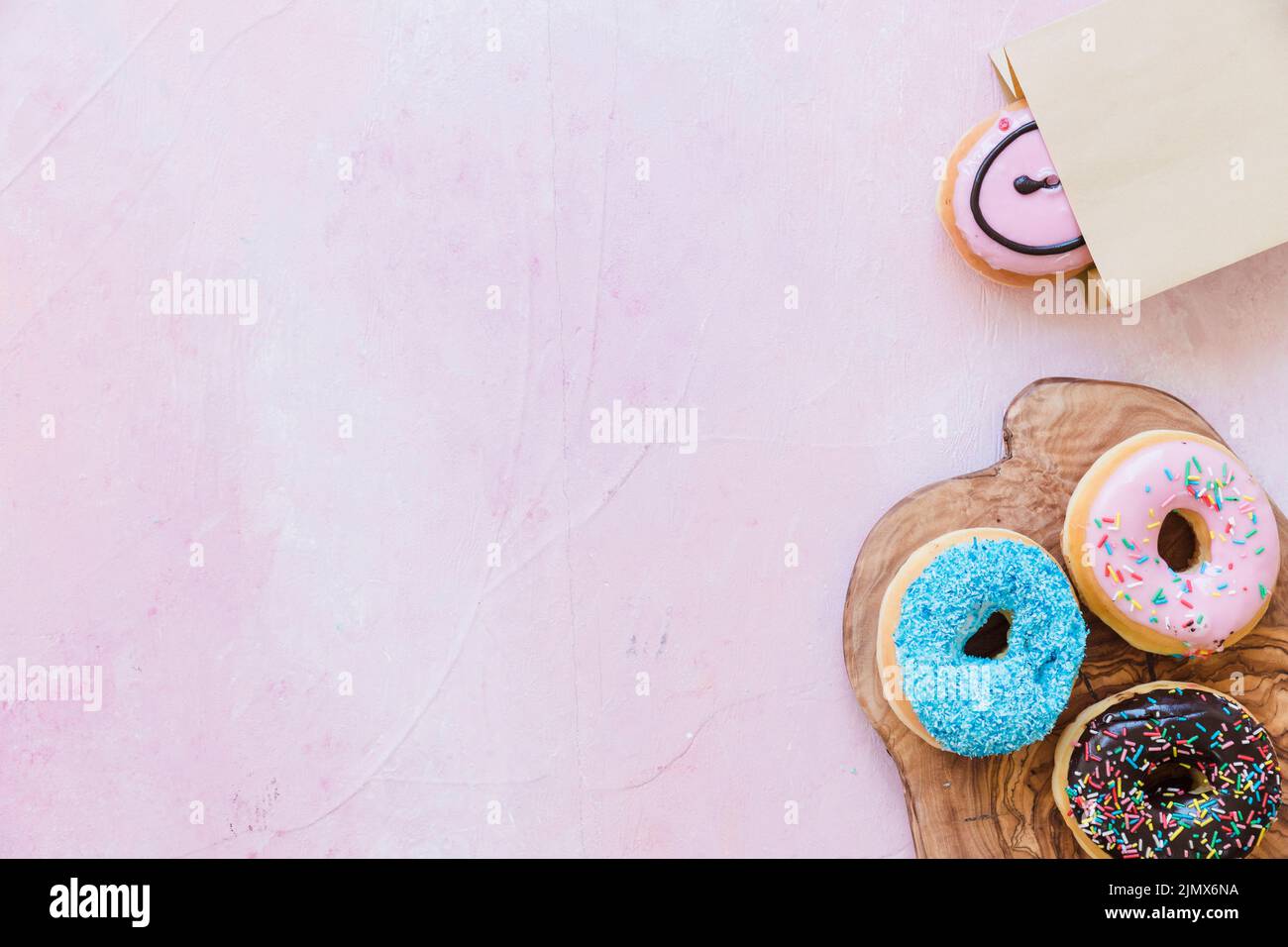 Fresh donuts chopping board near package pink background Stock Photo