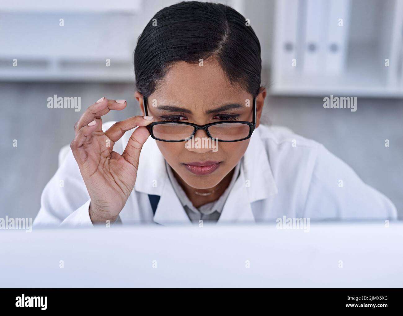 This cant be right... an attractive young female scientist looking stressed while working in her laboratory. Stock Photo