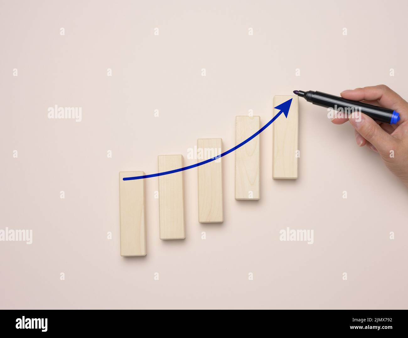 Graph with growing indicators and a female hand with a marker on a blue background. Stock Photo
