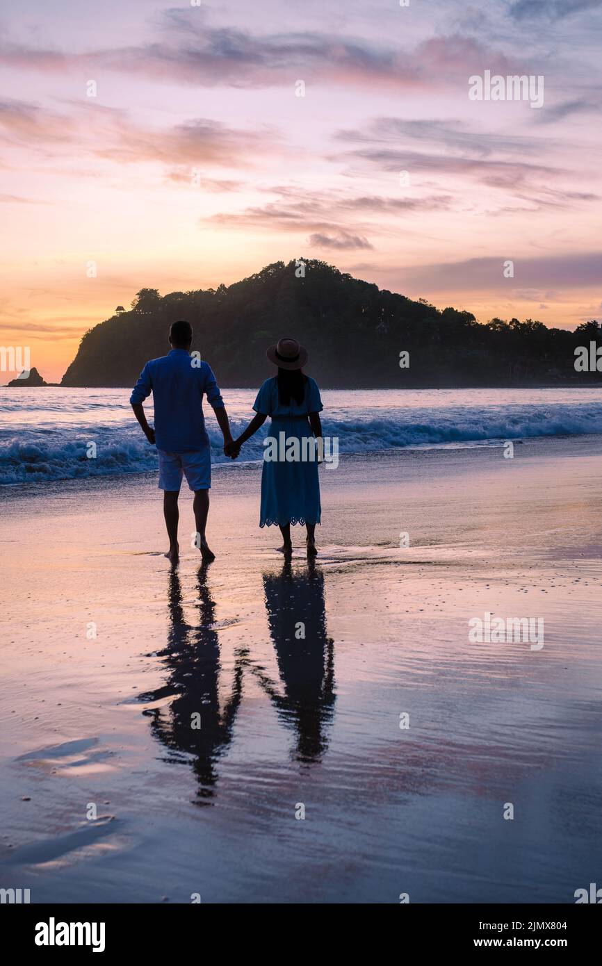 Couple men and woman looking at sunset on the beach of Koh Lanta Krabi Thailand Stock Photo