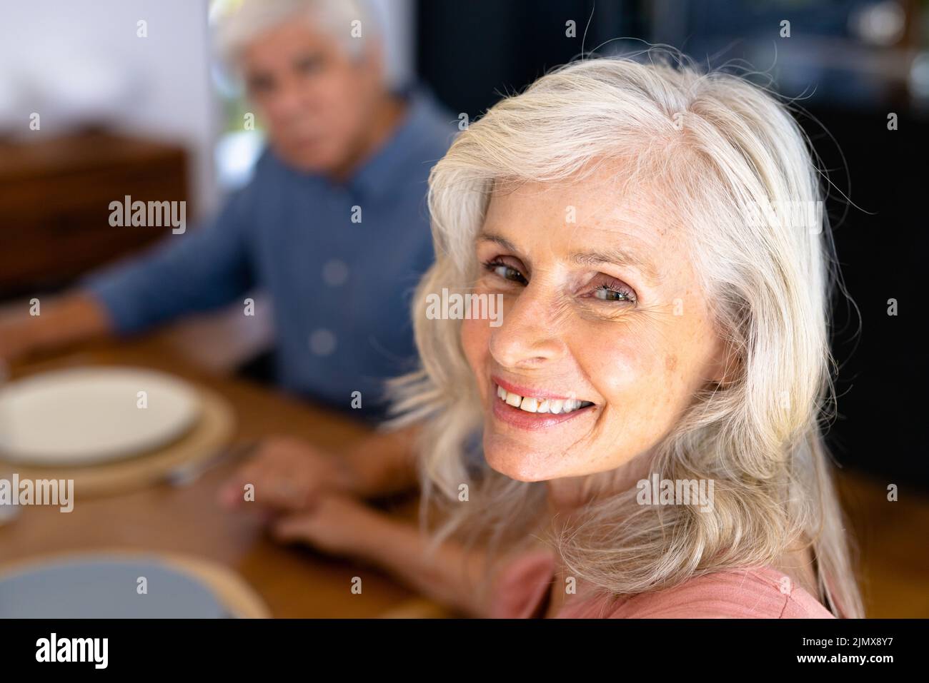 Close-up portrait of smiling caucasian senior woman holding biracial man's hand at dining table Stock Photo