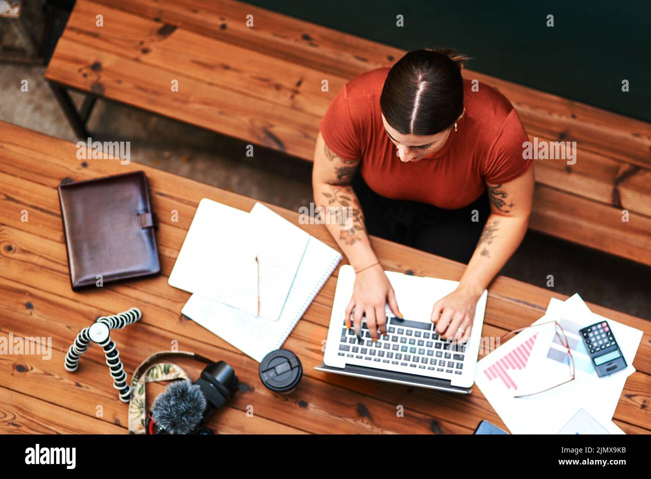 I always have such a busy workspace. High angle shot of an attractive young businesswoman sitting alone and blogging on her laptop. Stock Photo